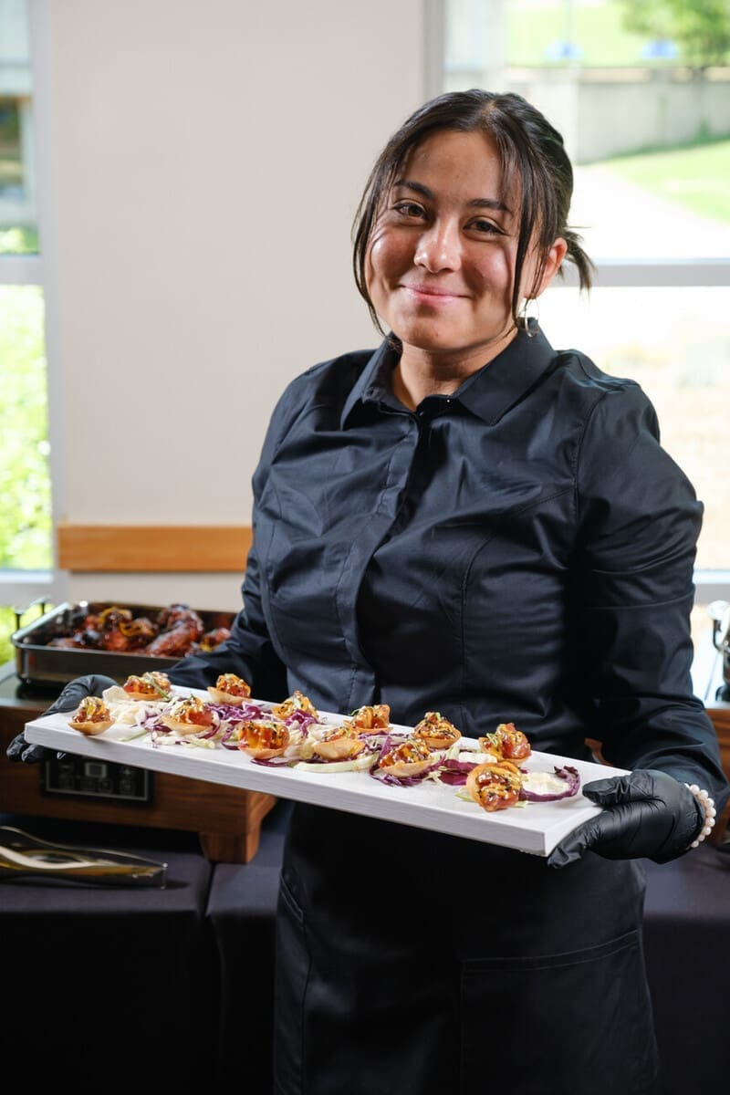 Employee smiling while holding a plate of hors d'oeuvres