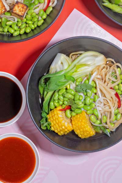 Overhead view of bowls of noodles with assorted vegetables